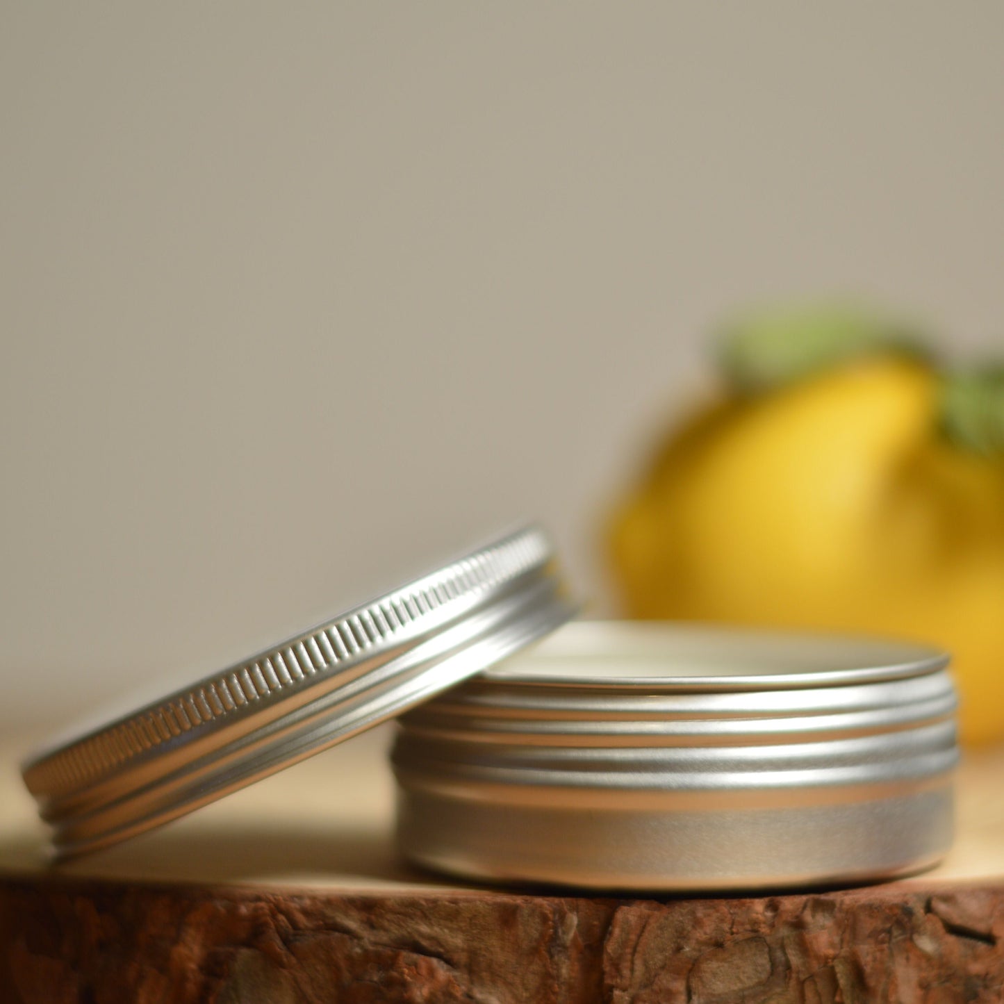 Tin of natural deodorant labeled 'flux' on a wooden surface with a lemon in the background.
