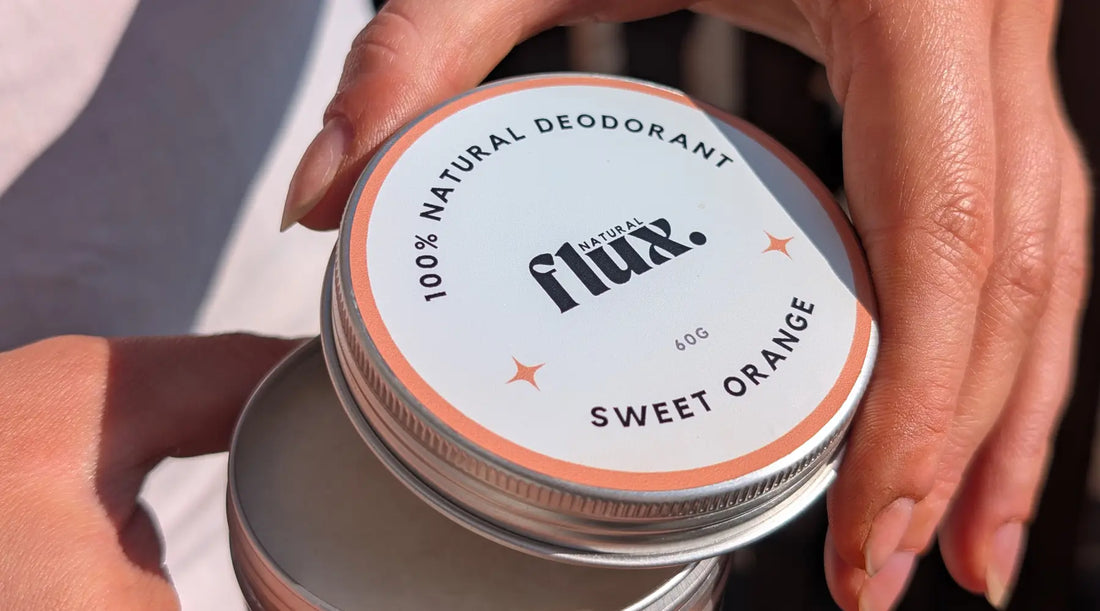 Hands holding a tin of Flux natural deodorant with Sweet Orange scent