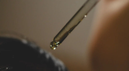 Close-up of a hair oil dropper dispensing oil onto hair