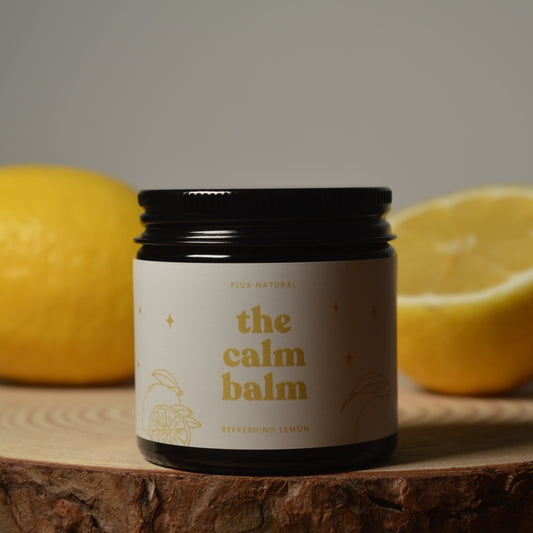 Jar of 'the calm balm' with lemons on a wooden surface
